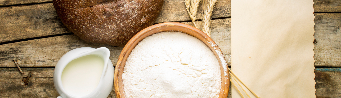 A bowl of flour with a jug of milk