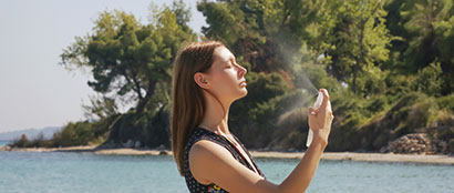 Woman applying spray sunscreen on the ocean shore