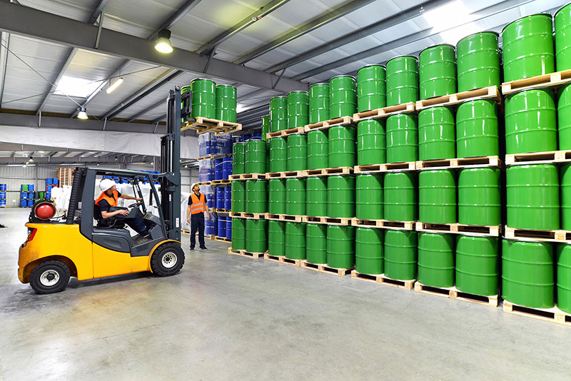 A forklift truck moving barrels in a warehouse