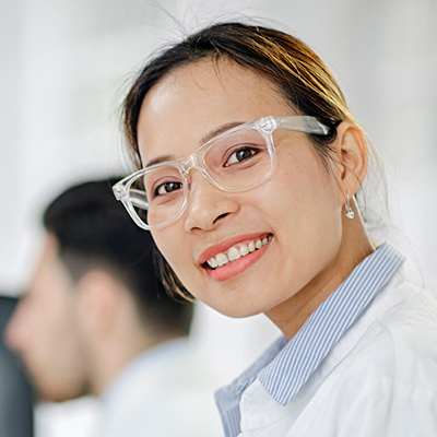 A lab scientist in PPE smiling at the camera