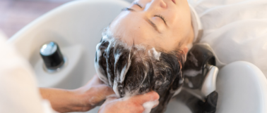 A hair salon employee rinses conditioner out of a customers hair